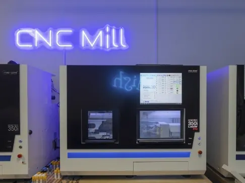 The CNC milling machines in the Ocean Oaks lab, under a neon CNC Mill sign.